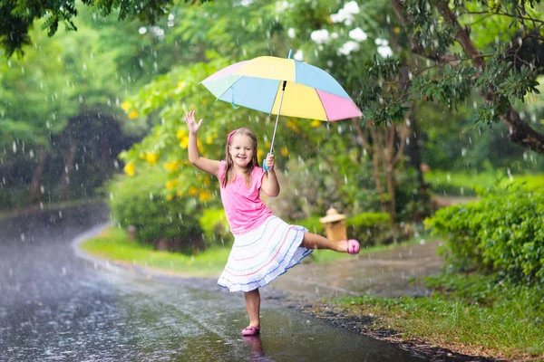 Criança com guarda-chuva jogando na chuva de verão . — Fotografia de Stock