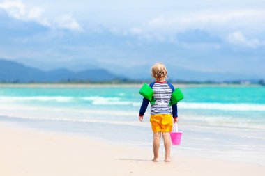 Çocuklar tropik sahilde oynar. Kum ve su oyuncak.