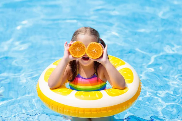 Kind im Schwimmbad. Kind isst Orange. — Stockfoto