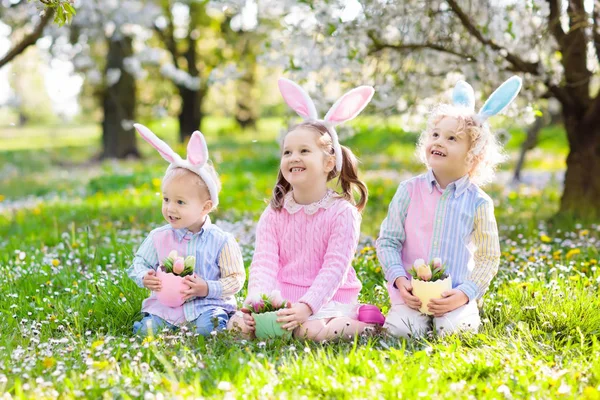 Eieren zoeken met Pasen. Kinderen met bunny oren en mand. — Stockfoto