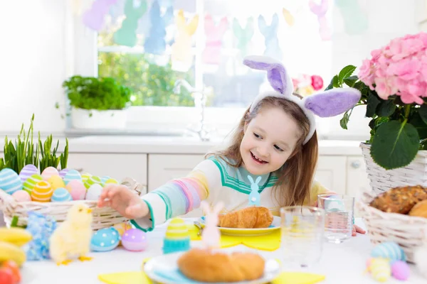 Kids at Easter breakfast. Eggs basket, bunny ears.