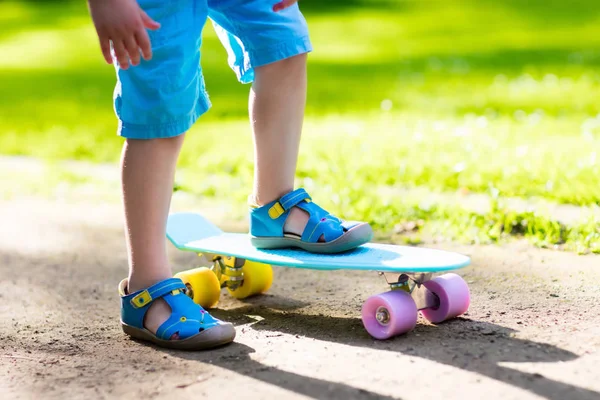 Child riding skateboard in summer park — Stock Photo, Image