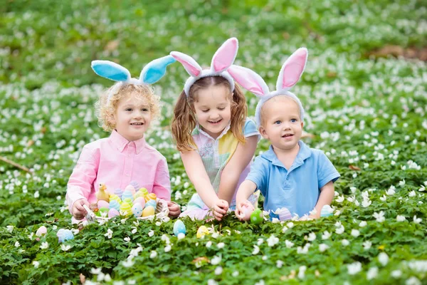 Діти з вухами кролика на полюванні на великодні яйця . — стокове фото
