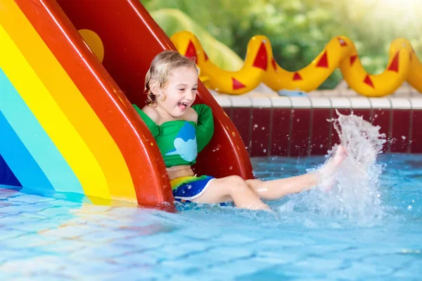 Bambino sullo scivolo della piscina. I bambini nuotano. Divertimento acqua — Foto Stock