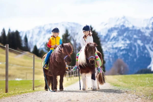 Miúdos a montar pónei. Criança a cavalo nas montanhas dos Alpes — Fotografia de Stock