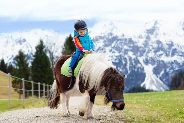 Miúdos a montar pónei. Criança a cavalo nas montanhas dos Alpes — Fotografia de Stock