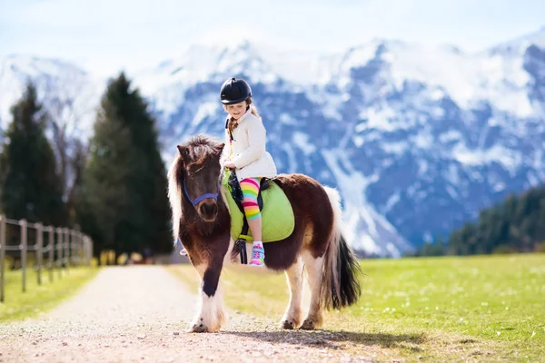 Miúdos a montar pónei. Criança a cavalo nas montanhas dos Alpes — Fotografia de Stock