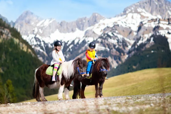 Niños montando pony. Niño a caballo en los Alpes montañas — Foto de Stock