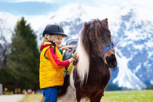 Niños montando pony. Niño a caballo en los Alpes montañas — Foto de Stock