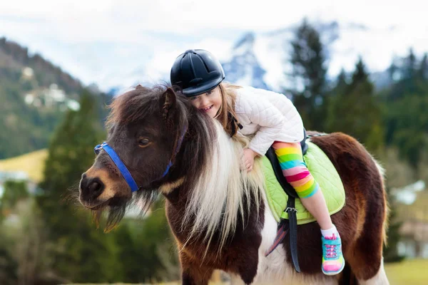 Дети катаются на пони. Ребенок на лошади в горах Альп — стоковое фото