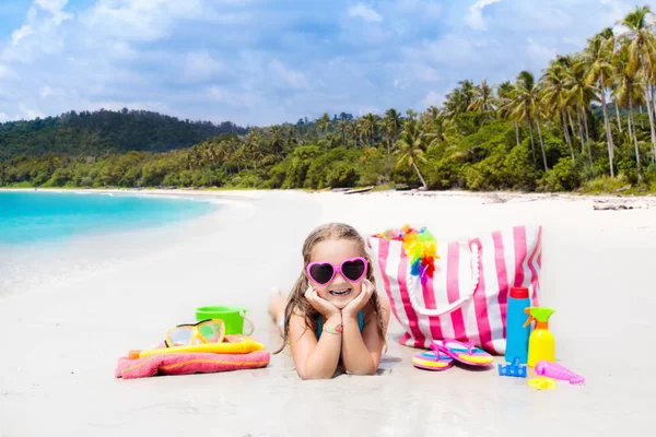 Child at tropical beach with bag and toys. — Stock Photo, Image