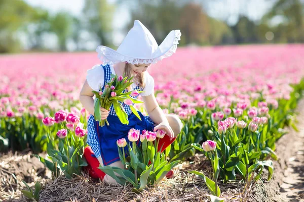 Child in tulip flower field. Windmill in Holland. — Stock Photo, Image