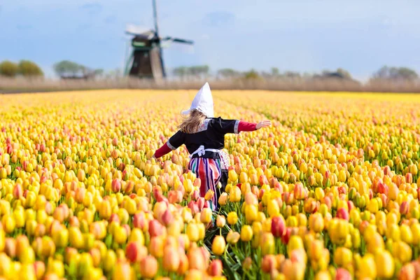 Child in tulip flower field. Windmill in Holland. — Stock Photo, Image