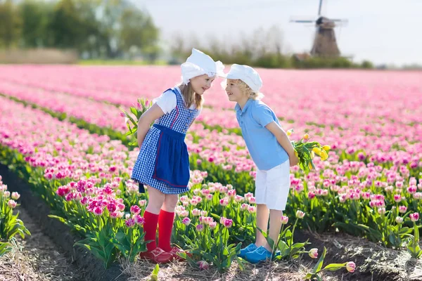 Kids in tulip flower field. Windmill in Holland — Stock Photo, Image