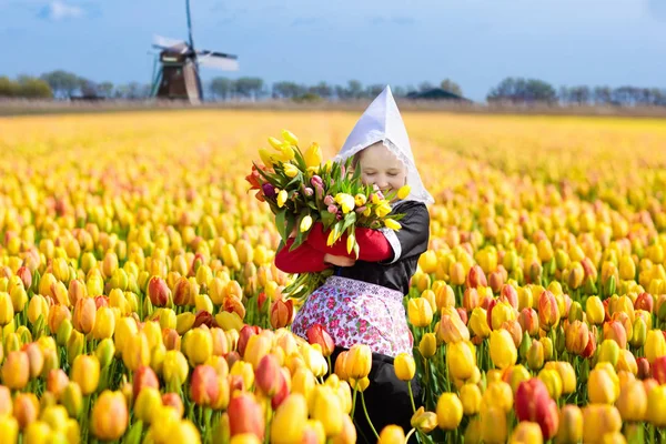 Kind in tulp bloem veld. Windmolen in Nederland. — Stockfoto