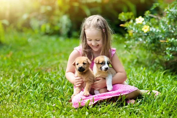 Los niños juegan con el cachorro. Niños y perros en el jardín . — Foto de Stock