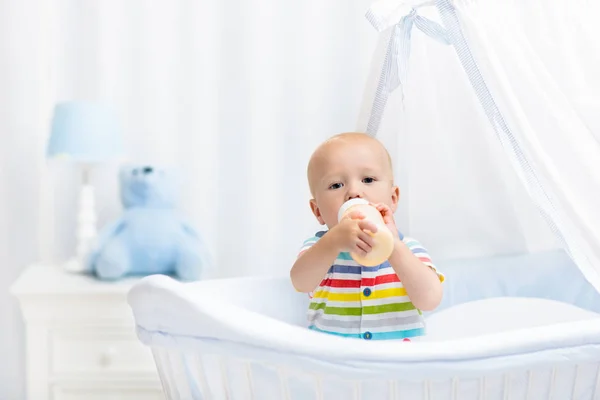 Bebê bebendo leite. Menino com garrafa de fórmula na cama — Fotografia de Stock