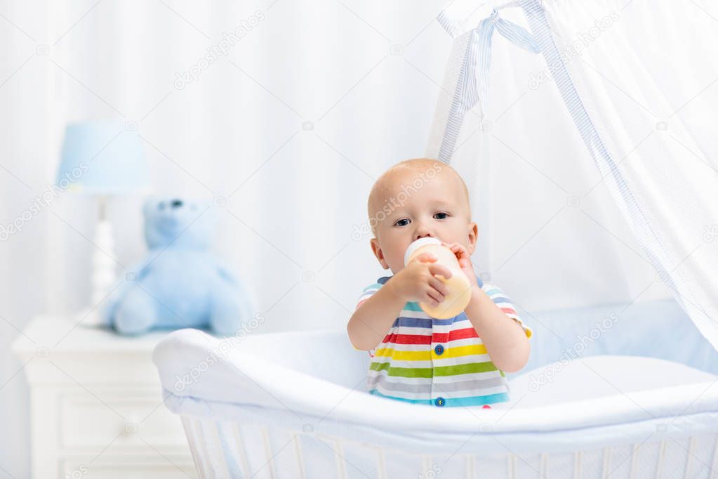 Baby drinking milk. Boy with formula bottle in bed