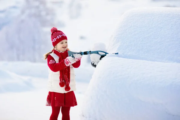 Criança a escovar o carro. Criança com escova de neve de inverno — Fotografia de Stock