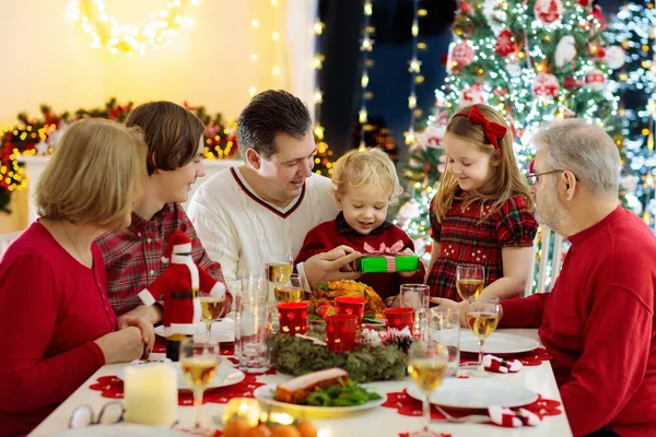 Familj med barn som äter julmiddag vid trädet — Stockfoto