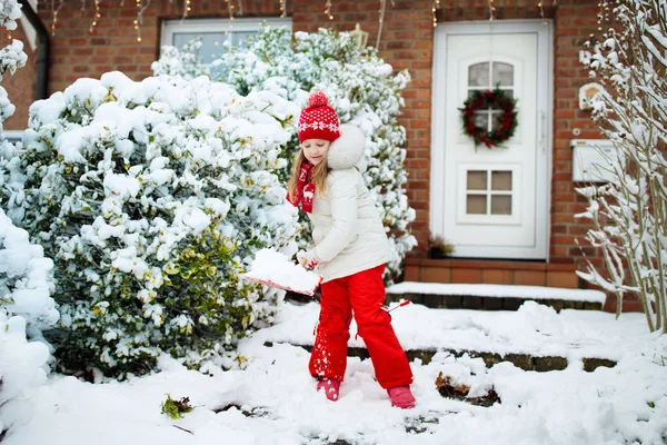 Niña paleando nieve de invierno. Niños despejen la entrada . —  Fotos de Stock