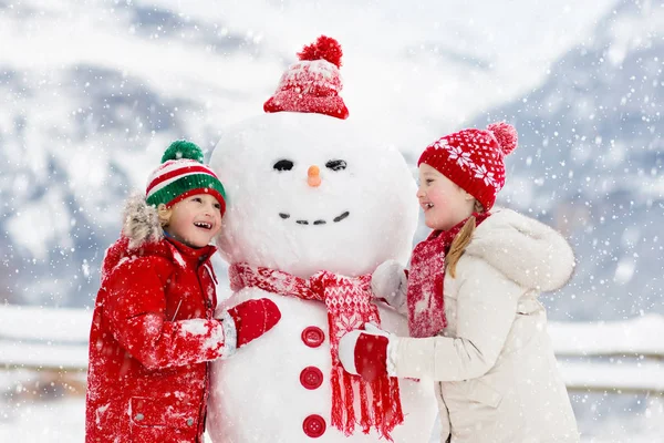Child building snowman. Kids build snow man. — Stock Photo, Image