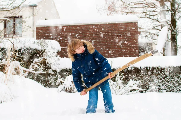 Een kind dat wintersneeuw schept. Kinderen veilig oprit. — Stockfoto