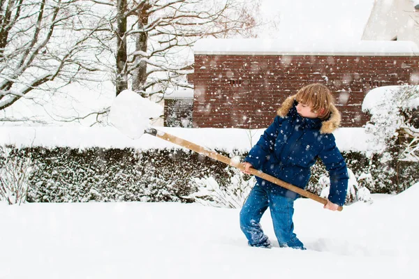 Kışın kar kürüyen çocuk. Çocuklar garaj yolunu temizliyor. — Stok fotoğraf