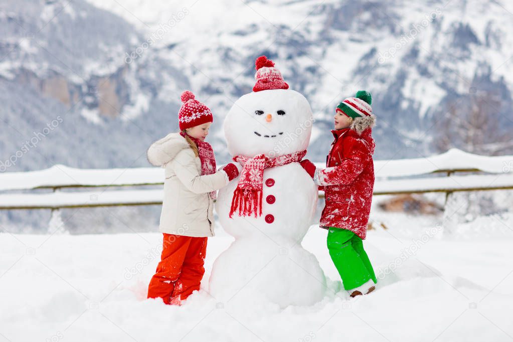 Child building snowman. Kids build snow man. 
