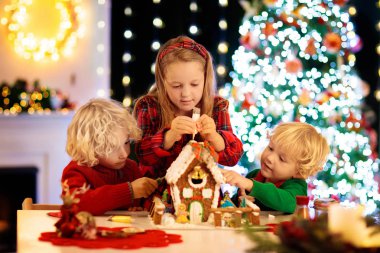 Çocuklar zencefilli kurabiye evi yapıyor. Evde Noel.