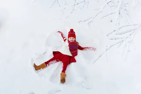 Niño haciendo ángel de nieve. Niños invierno diversión al aire libre . —  Fotos de Stock