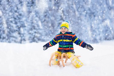 Kızak süren çocuk. Çocuk kayağı. Kızaklı çocuk.