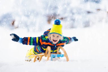 Kızak süren çocuk. Çocuk kayağı. Kızaklı çocuk.