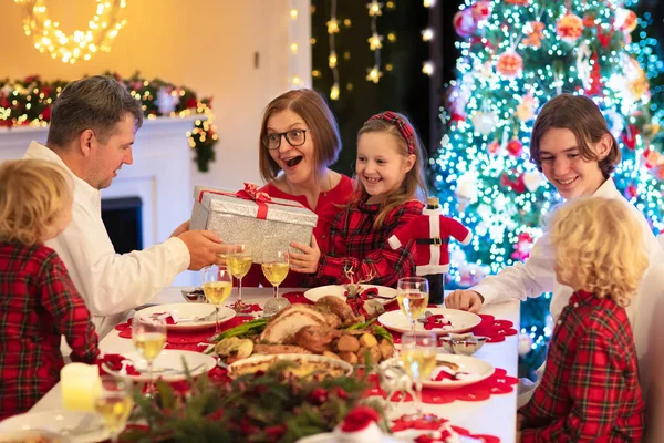 Family with kids having Christmas dinner at tree — Stock Photo, Image