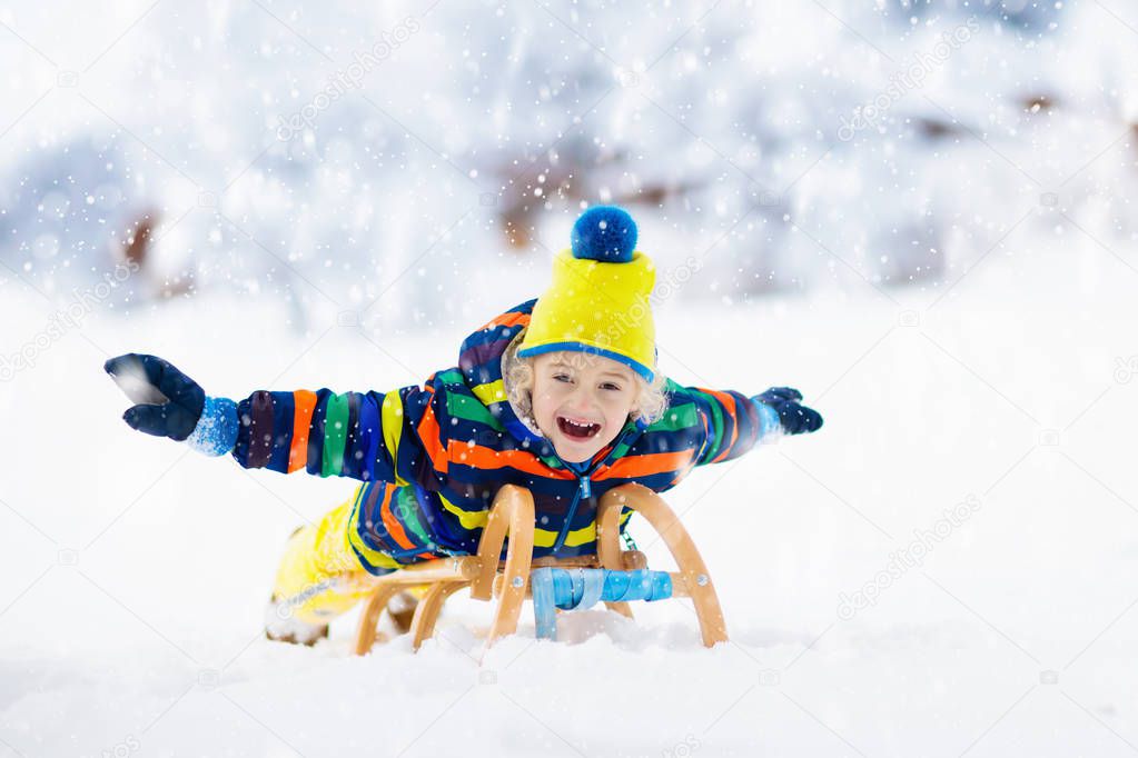 Boy on sled ride. Child sledding. Kid on sledge