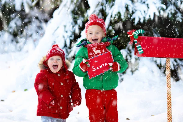 Child with letter to Santa at Christmas mail box in snow — Stock Photo, Image