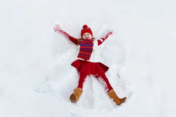 Criança fazendo anjo da neve. Crianças inverno diversão ao ar livre . — Fotografia de Stock