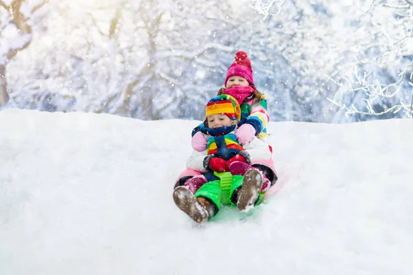 Dzieci bawią się w śniegu. Zimowa przejażdżka sankami dla dzieci — Zdjęcie stockowe