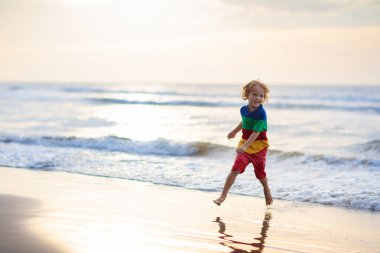 Okyanus plaj üzerinde oynayan çocuk. Gün batımı denizde evlat.