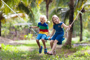 Kids on swing. Playground in tropical resort.
