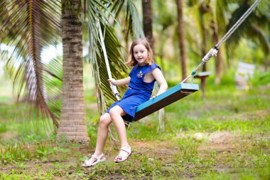 Kids on swing. Playground in tropical resort.