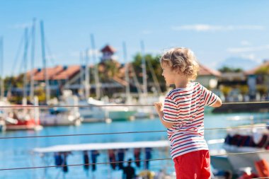 Child watching yacht and boat in harbor. Yachting.