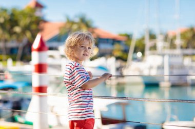 Child watching yacht and boat in harbor. Yachting.