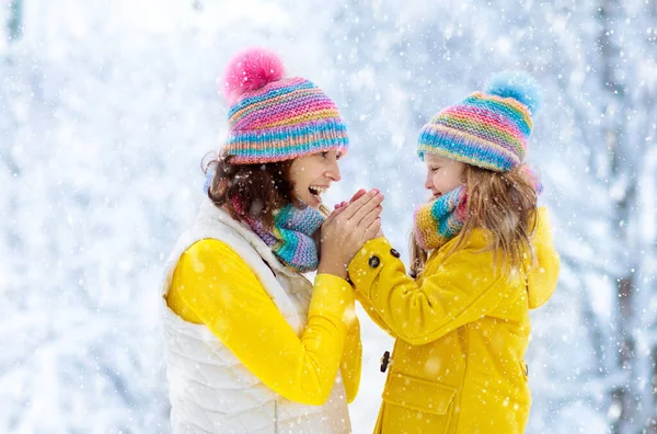 Moeder en kind in gebreide winter hoeden in sneeuw. — Stockfoto