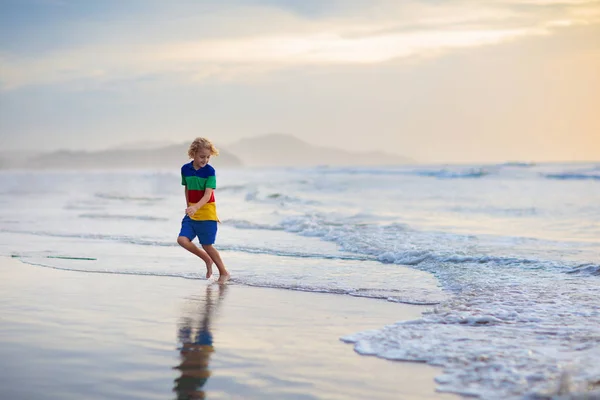 Child playing on ocean beach. Kid at sunset sea. — Stock Photo, Image