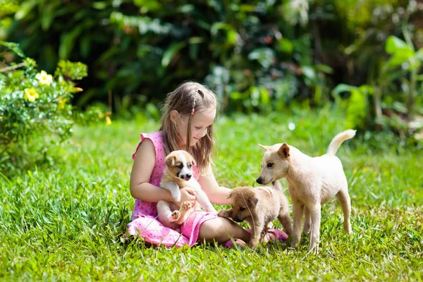 Les enfants jouent avec le chiot. Enfants et chien dans le jardin . — Photo