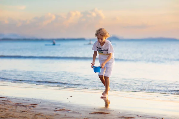 As crianças brincam na praia tropical. Brinquedo de areia e água . — Fotografia de Stock