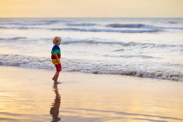 Niño jugando en la playa del océano. Niño al atardecer mar . —  Fotos de Stock