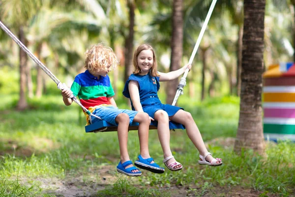 Kinderen op swing. Speeltuin in tropisch resort. — Stockfoto