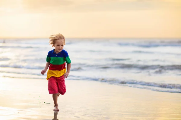 Niño jugando en la playa del océano. Niño al atardecer mar . —  Fotos de Stock